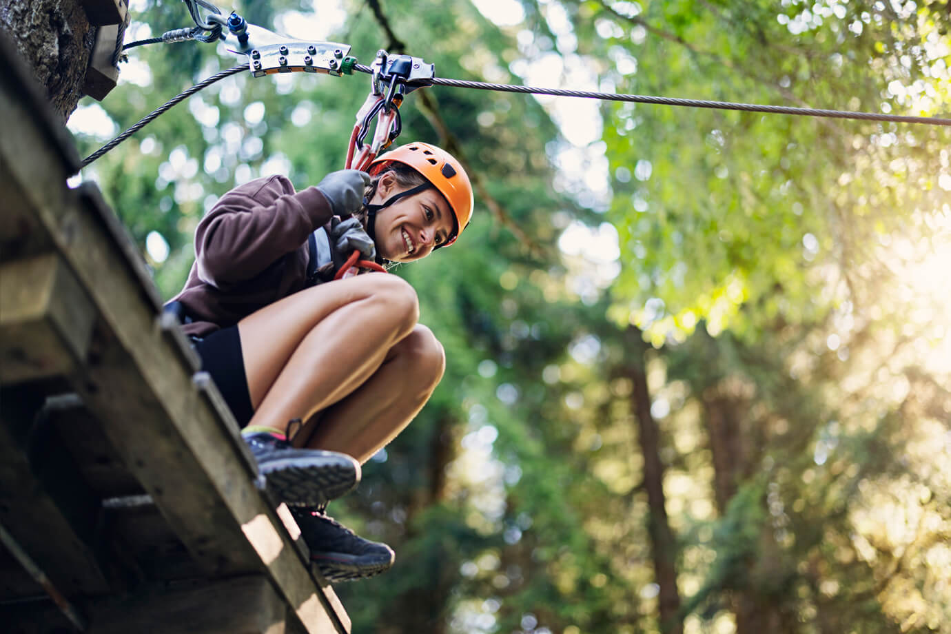 Junge Frau im Hochseilgarten an Zipline