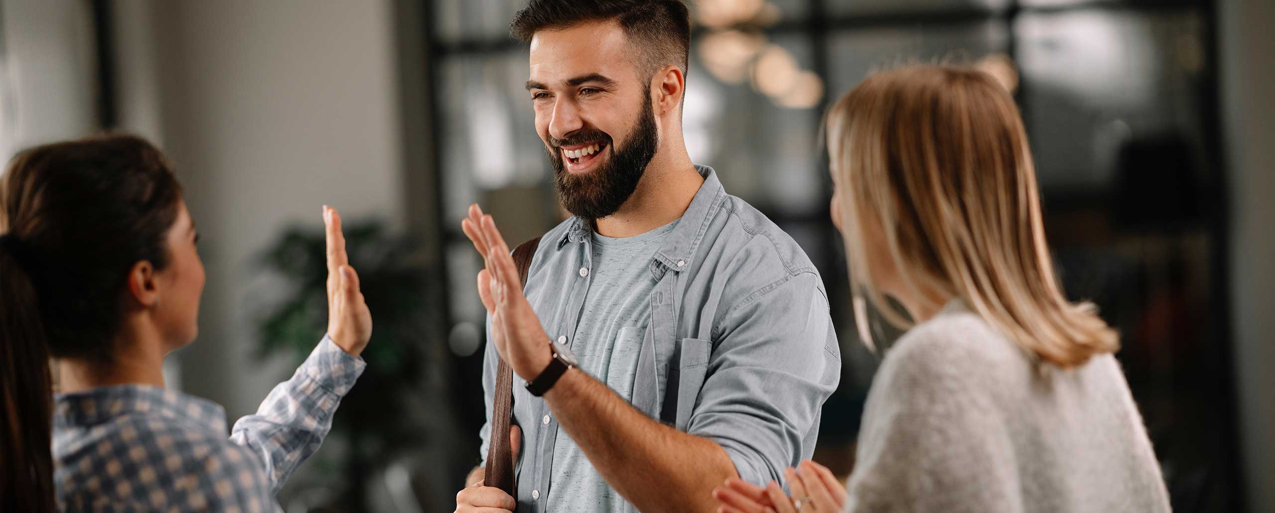 Drei Menschen freuen sich im B&uuml;ro nach erfolgreichem Teamwork 