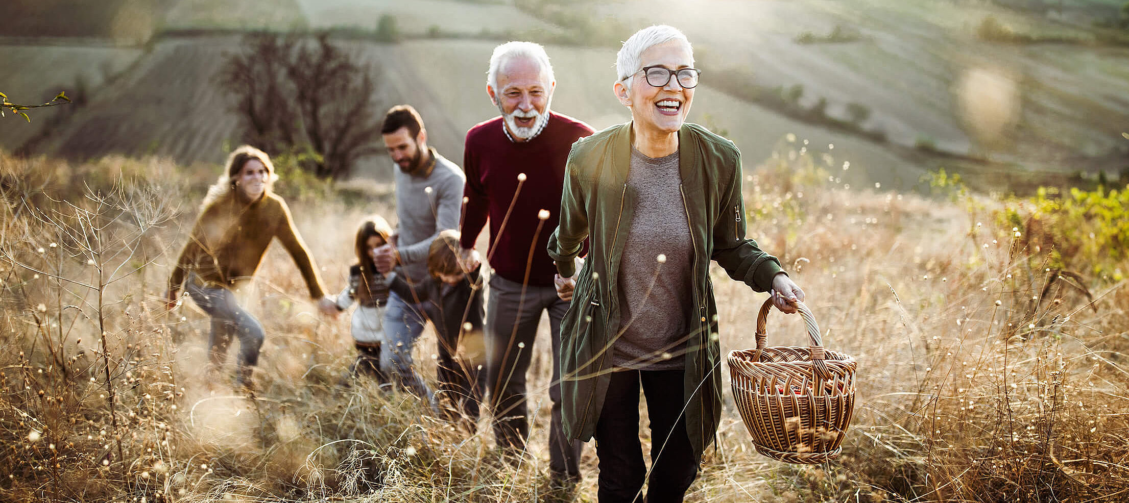 Gl&uuml;ckliche Seniorin f&uuml;hrt Familie zum Picknick im Feld
