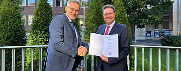 Der Dekan der Wirtschaftswissenschaftlichen Fakult&auml;t der Universit&auml;t M&uuml;nster, Prof. Dr. Thomas Langer, &uuml;berreicht Dr. Volker Heinke die Ernennungsurkunde.