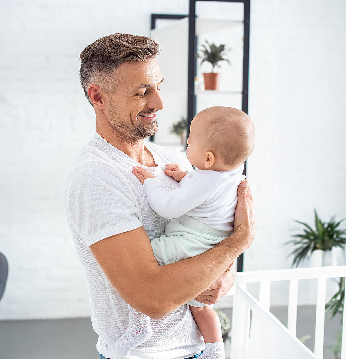 Junger Vater h&auml;lt Baby auf dem Arm