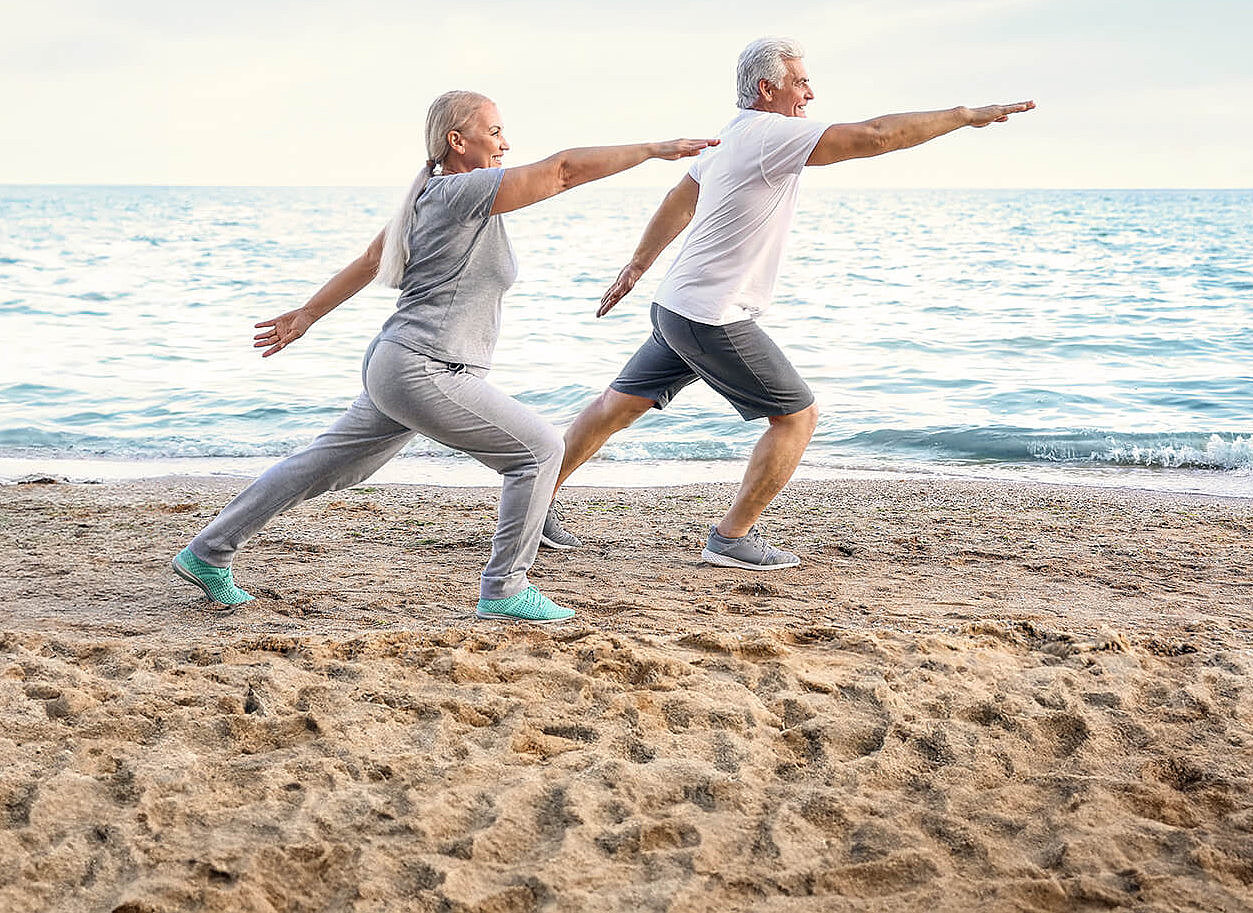 &Auml;lteres Paar macht Yoga am Strand
